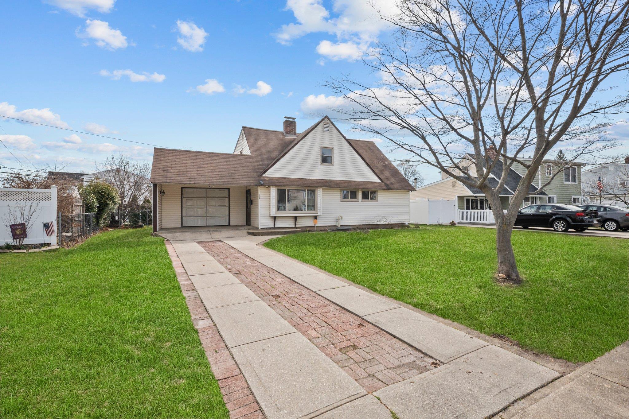 View of front of home featuring concrete driveway, a garage, fence, and a front lawn