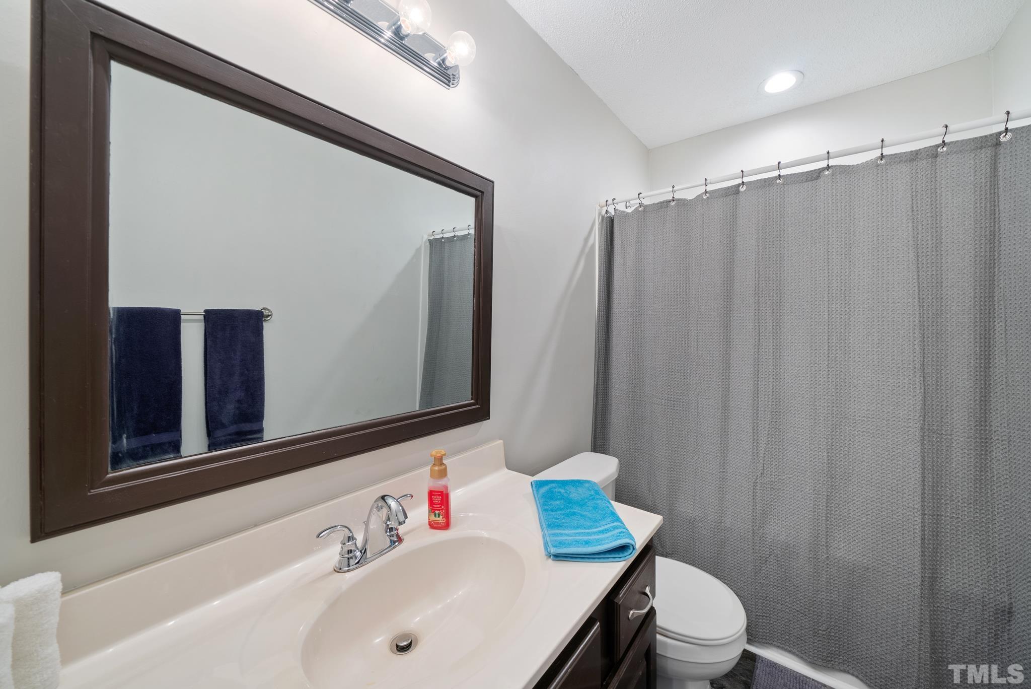 8205 Bellingham Circle Raleigh, NC 27615 - Photo 14 of 16 a bathroom with a sink a toilet a mirror and shower curtain