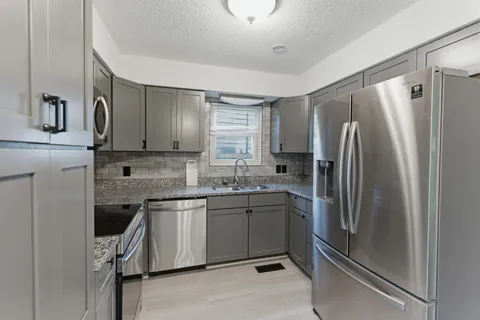 a kitchen with stainless steel appliances granite countertop a refrigerator and a sink