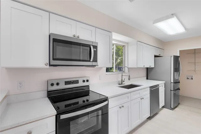 a kitchen with stainless steel appliances a stove microwave and sink