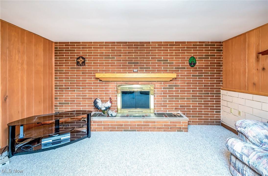 126 South Rhodes Avenue Niles, OH 44446 - Photo 21 of 23 Unfurnished living room featuring carpet floors, brick wall, and wooden walls