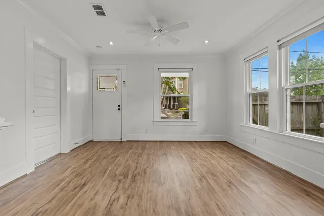 an empty room with wooden floor and windows