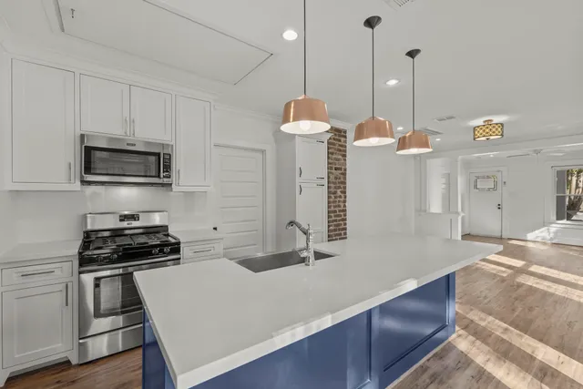 a kitchen with kitchen island a counter space a sink appliances and cabinets