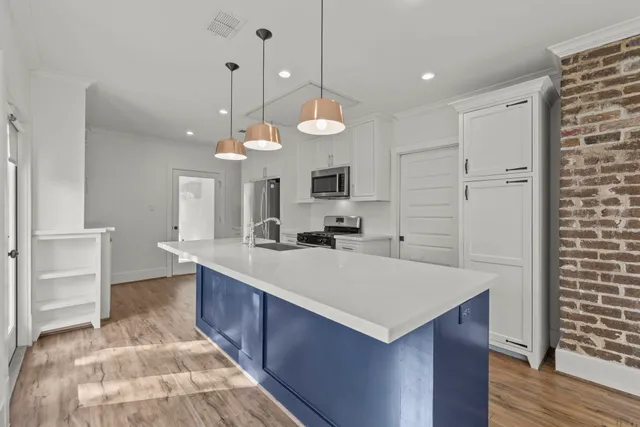 a large kitchen with kitchen island a stove a sink a center island a refrigerator and a fireplace