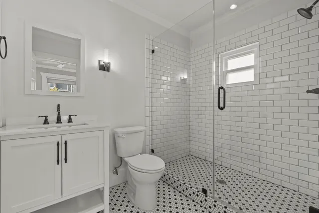 a bathroom with a toilet a sink a mirror and shower