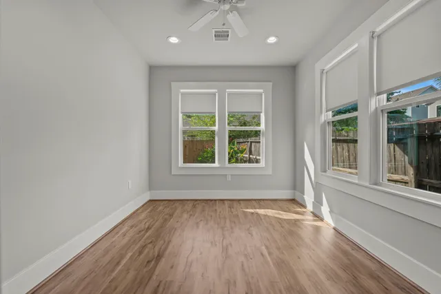 a view of an empty room with wooden floor and a window