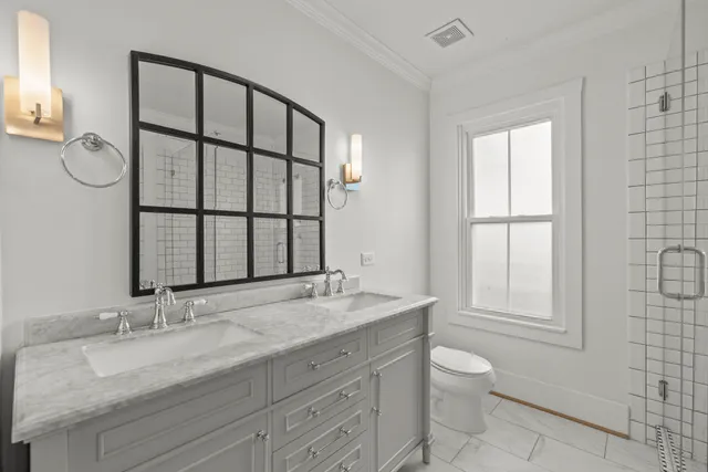 a bathroom with a granite countertop toilet a sink a mirror and a window