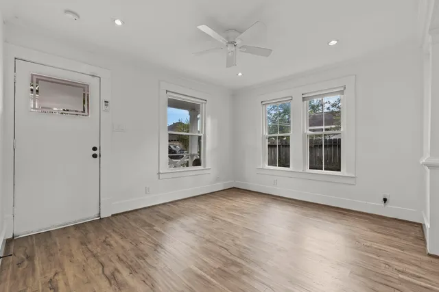 a view of an empty room with wooden floor and a window