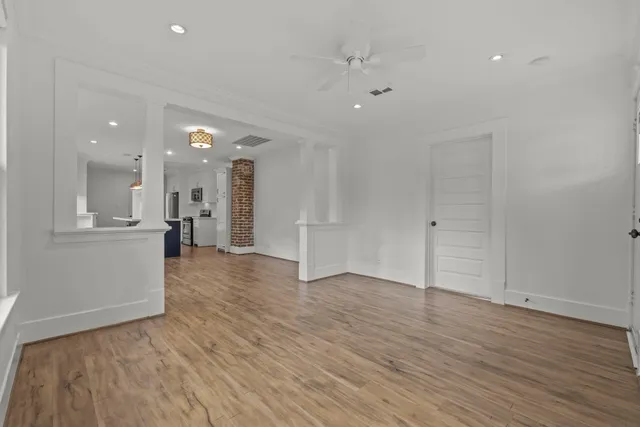 a view of a big room with wooden floor and a kitchen