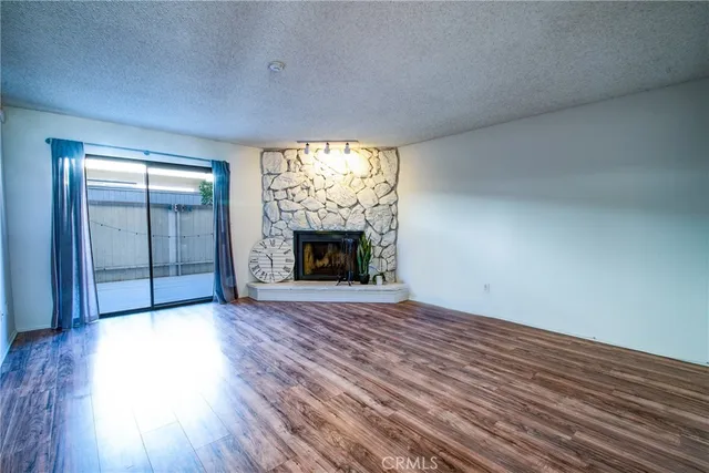 an empty room with wooden floor fireplace and windows