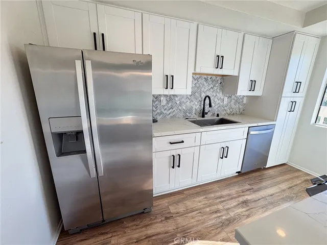 a kitchen with stainless steel appliances granite countertop a refrigerator a sink and white cabinets