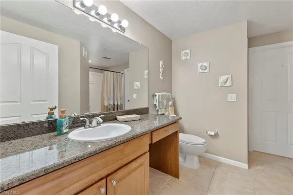 a bathroom with a granite countertop sink a toilet and a mirror