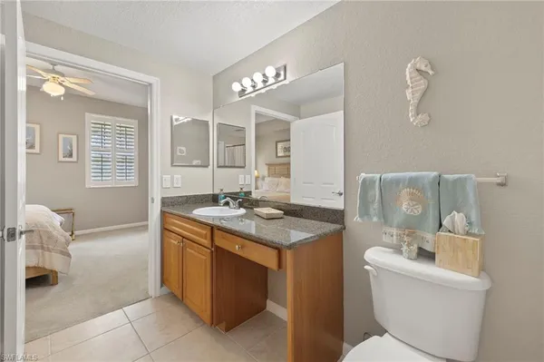 a bathroom with a granite countertop sink a toilet and a mirror