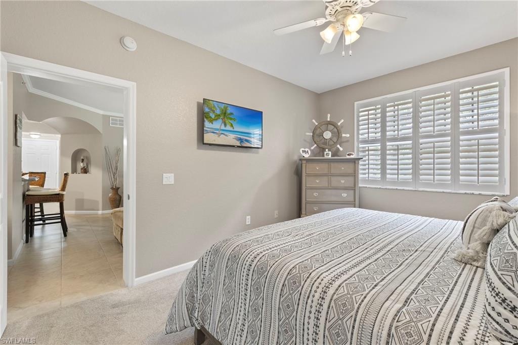 12955 Positano Circle, Unit 104 Naples, FL 34105 - Photo 18 of 40 a bedroom with a bed and a chandelier