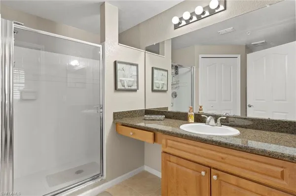 a bathroom with a granite countertop sink a mirror and a shower