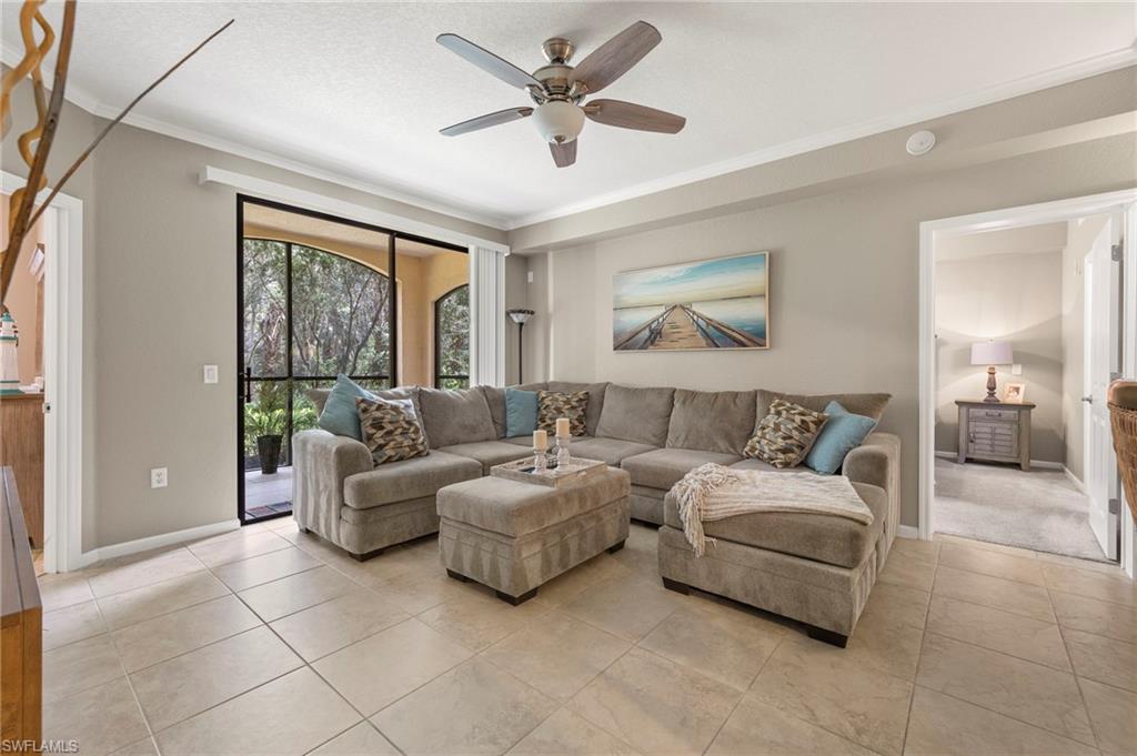 12955 Positano Circle, Unit 104 Naples, FL 34105 - Photo 4 of 40 a living room with furniture and a large window with a chandelier