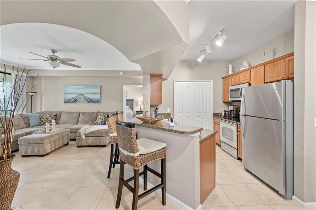 12955 Positano Circle, Unit 104 Naples, FL 34105 - Photo 7 of 40 a kitchen with a refrigerator a stove a dining table and chairs