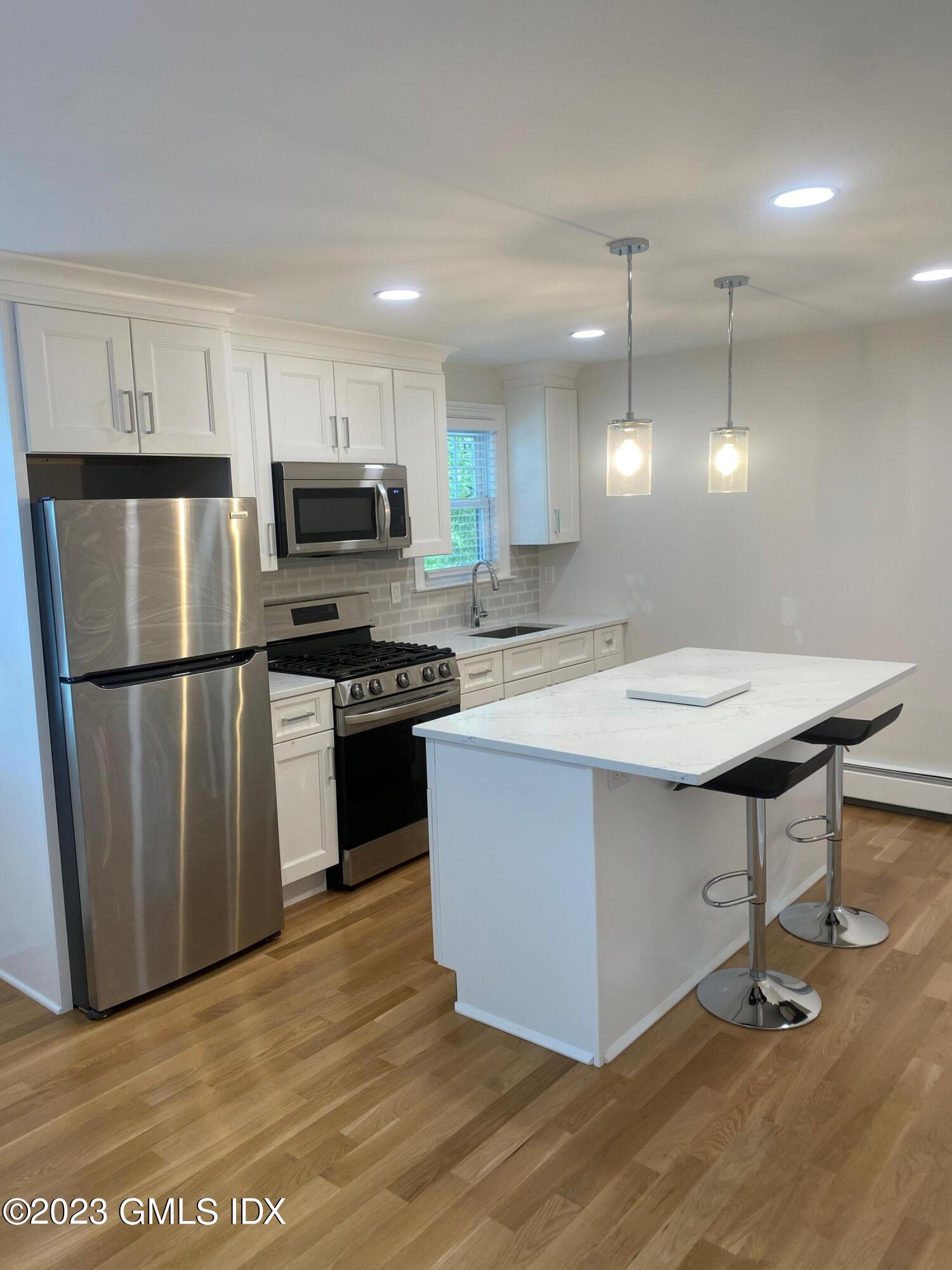 a kitchen with a sink a refrigerator and a stove top oven with wooden floor