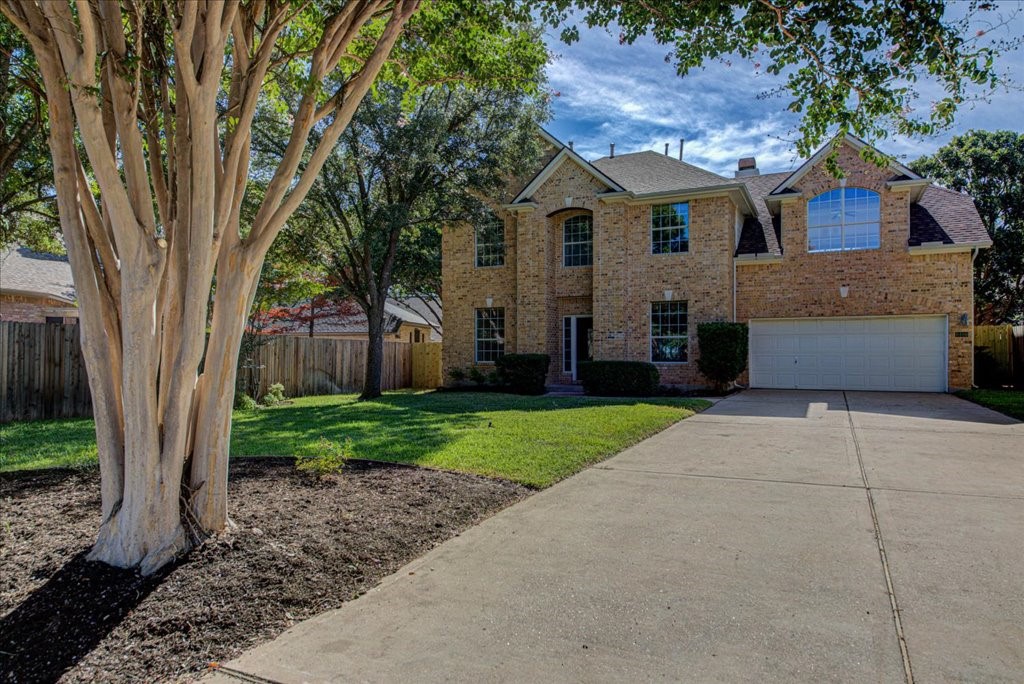 a front view of a house with a garden and trees
