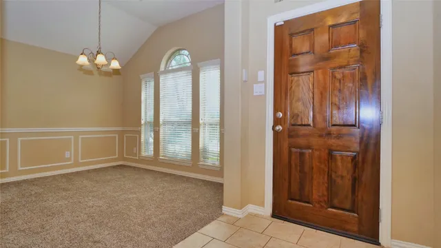 an empty room with chandelier fan and windows