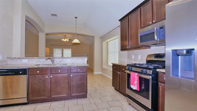 a kitchen with stainless steel appliances granite countertop a stove a sink and a microwave