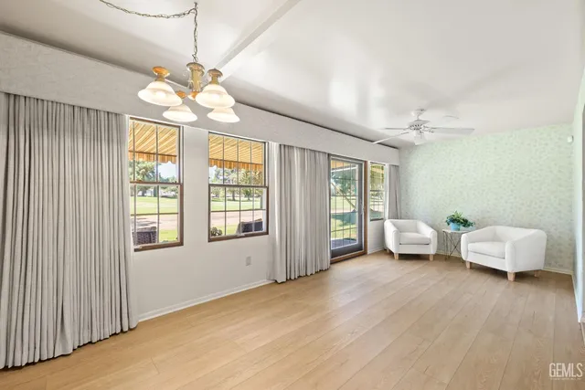 a view of an empty room with window chandelier fan and wooden floor