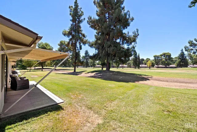 a view of swimming pool with lawn chairs under an umbrella