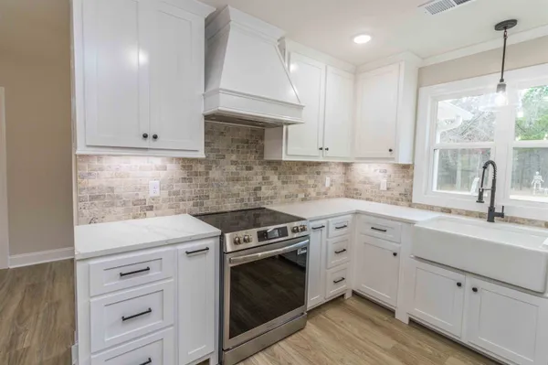 a kitchen with cabinets appliances a sink and a window