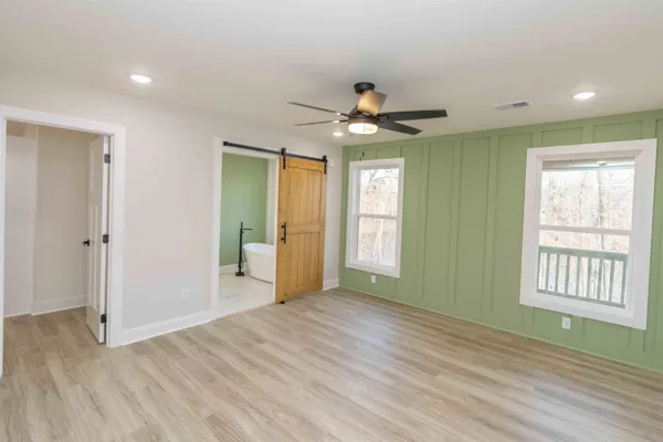 a view of an empty room with a window and wooden floor