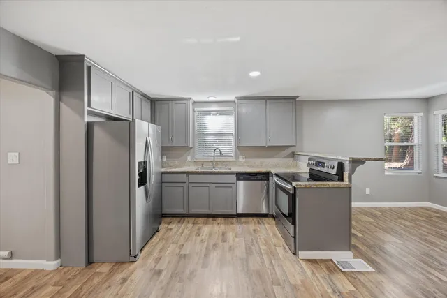 a kitchen with granite countertop a refrigerator stove top oven and sink