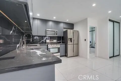 a kitchen with stainless steel appliances granite countertop a refrigerator a stove and a sink