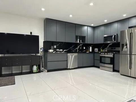 a kitchen with stainless steel appliances a refrigerator a sink a stove top oven a counter space and cabinets