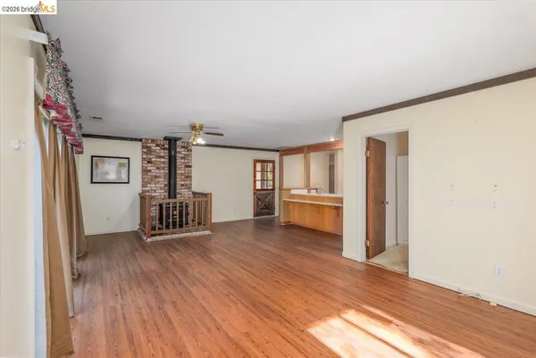 a view of an empty room with window and wooden floor