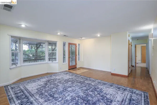 a view of an empty room and window and wooden floor
