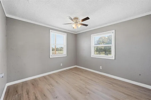 a view of an empty room with window and wooden floor