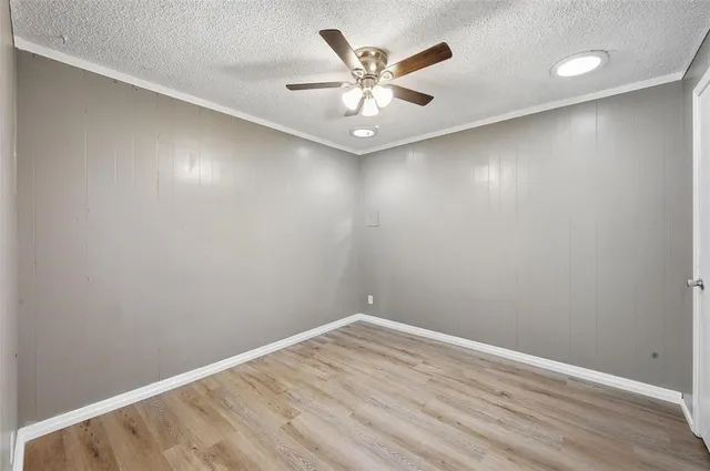 an empty room with a ceiling fan and wooden floor