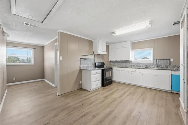 a large kitchen with a wooden floor a sink stainless steel appliances and cabinets