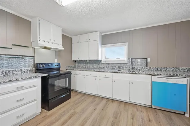 a kitchen with granite countertop wooden cabinets and a stove