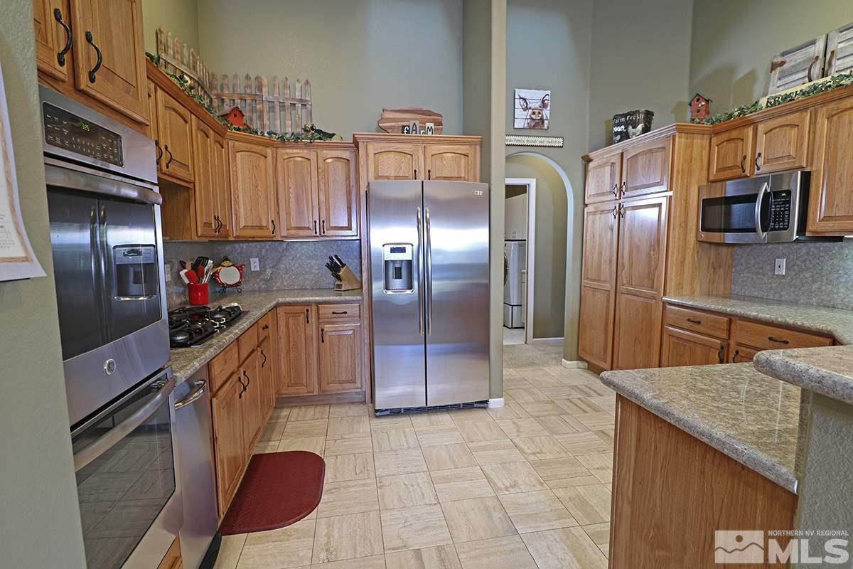 55 Water Lily Court Reno, NV 89511 - Photo 7 of 25 a kitchen with stainless steel appliances granite countertop a refrigerator a stove and a sink with cabinets