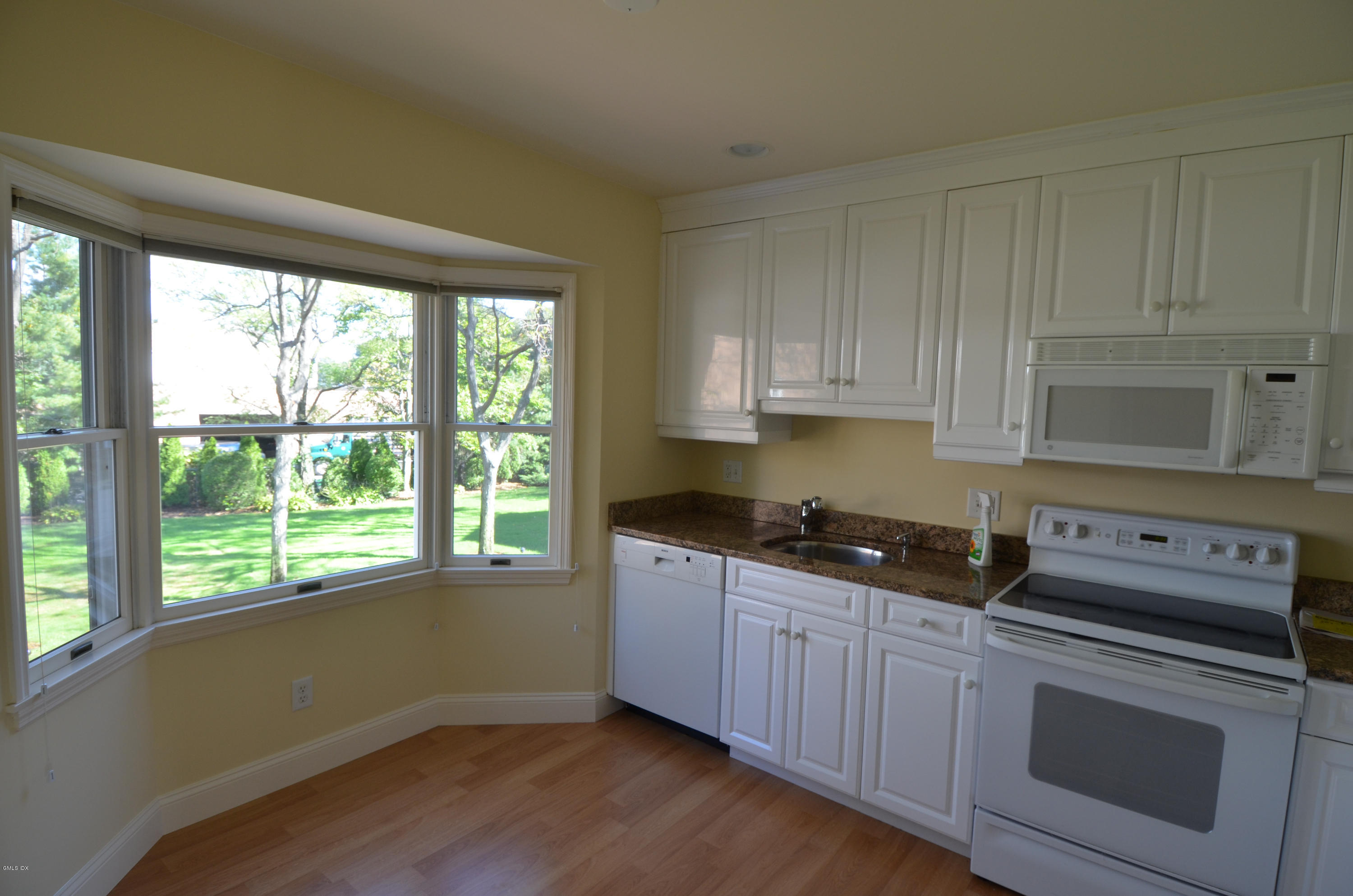 115 River Road, Unit 10 Cos Cob, CT 06807 - Photo 9 of 19 a kitchen with granite countertop wooden cabinets appliances and a large window