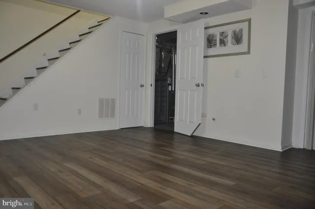 a view of an empty room with wooden floor and stairs