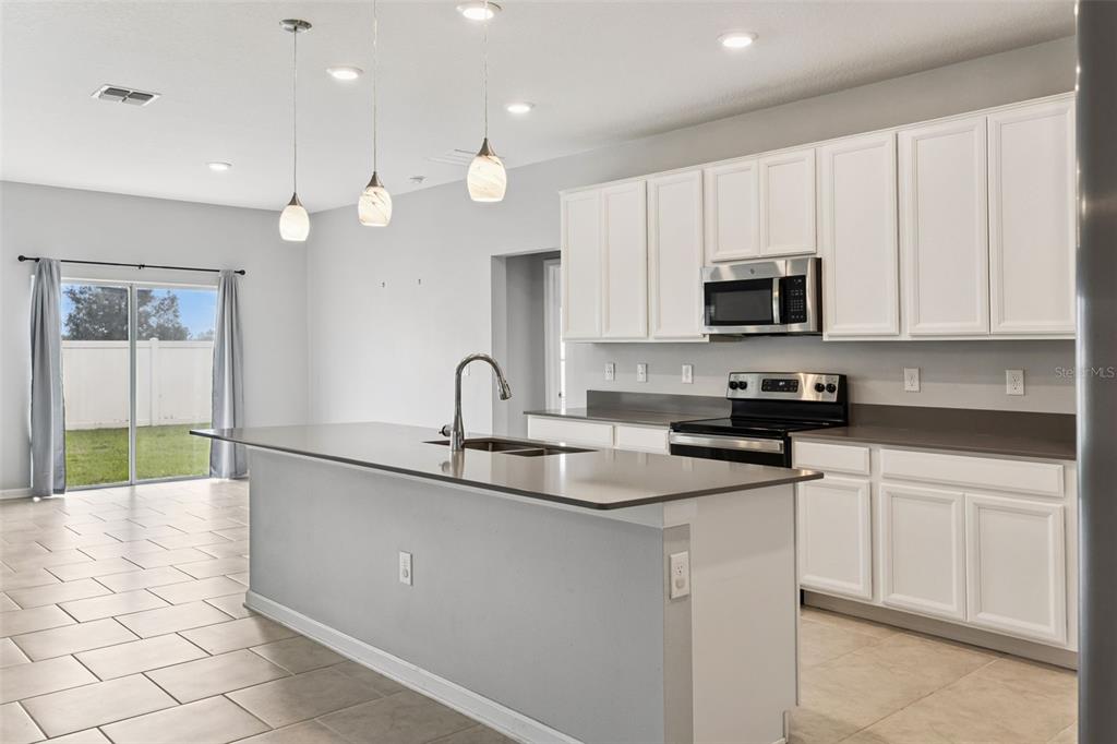 781 Taurus Lane St. Cloud, FL 34772 - Photo 8 of 36 a kitchen with kitchen island granite countertop a sink a stove and cabinets