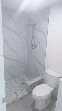 a white toilet sitting next to a bath tub and shower