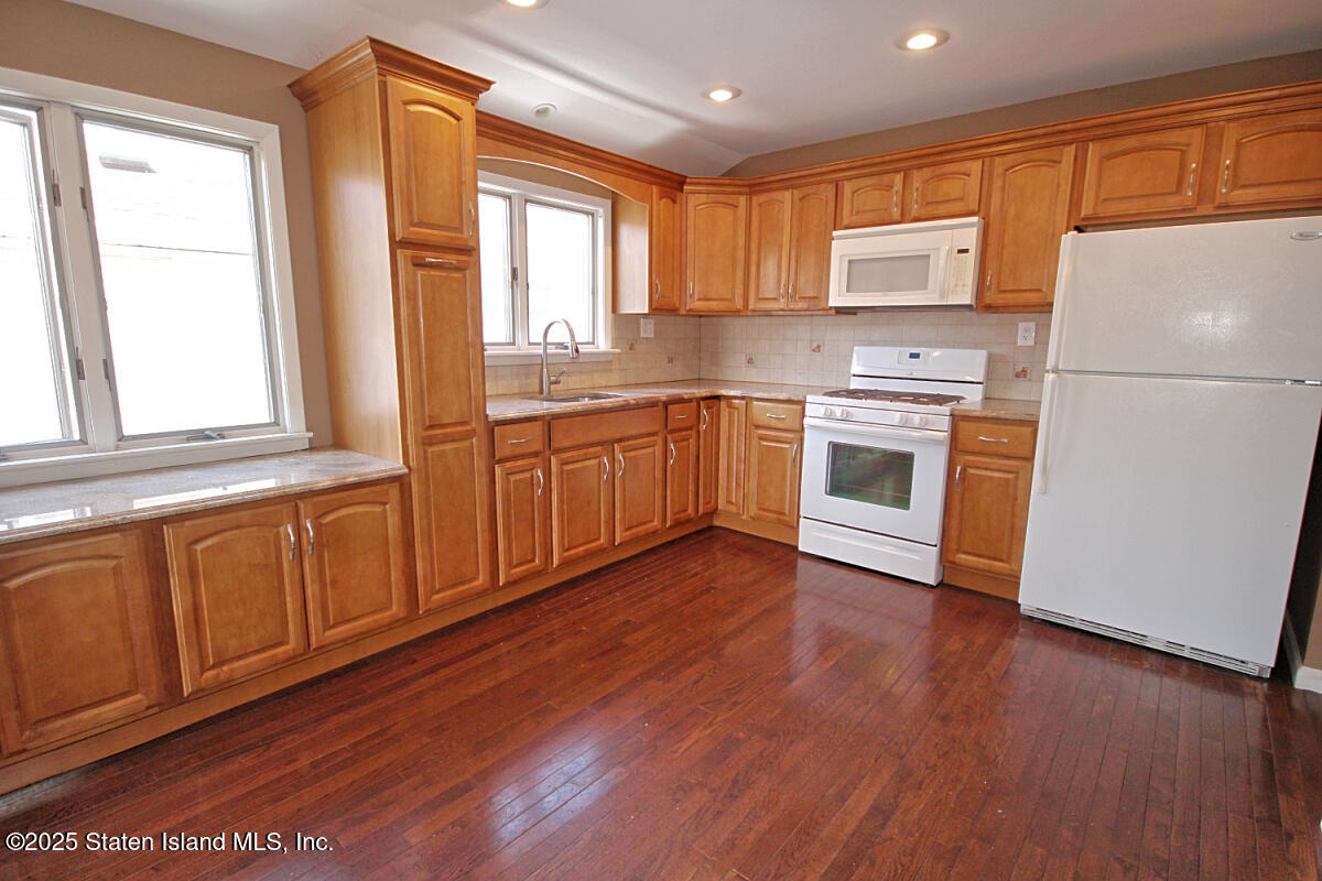 3 Windermere Road Staten Island, NY 10305 - Photo 7 of 37 a kitchen with granite countertop wooden floors white stainless steel appliances a sink and a window