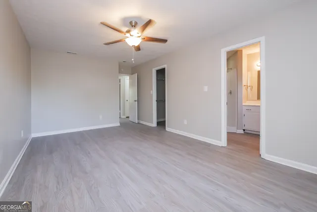 an empty room with wooden floor and a ceiling fan