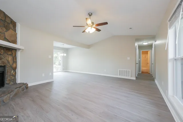 a view of an empty room with window and wooden floor