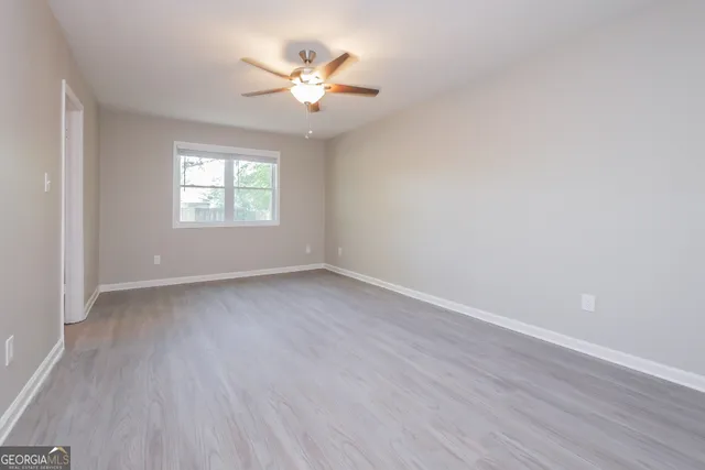 an empty room with wooden floor and windows