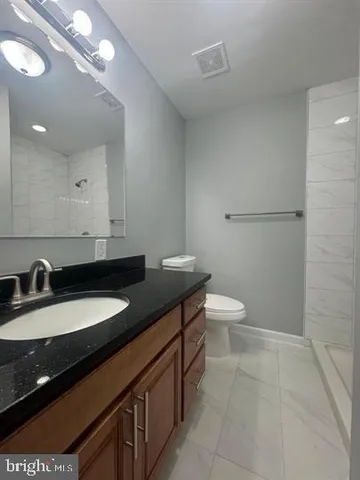 a bathroom with a granite countertop sink a toilet and a mirror