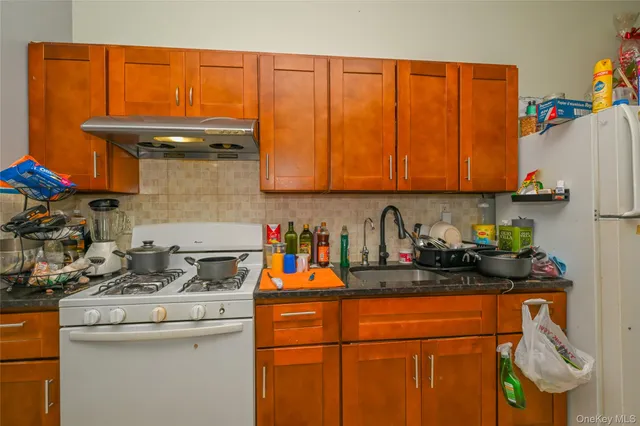 a kitchen with stainless steel appliances granite countertop a stove top oven a sink dishwasher and a microwave with wooden cabinets