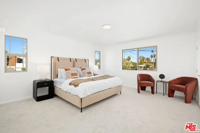 a white bed sitting in a bedroom next to a couch